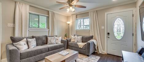 A living room with two grey sofas, a wooden coffee table, and a ceiling fan.