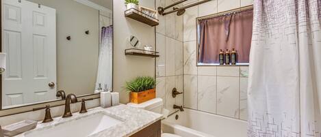 A bathroom with a double sink, a toilet, a bathtub, and a shower curtain.