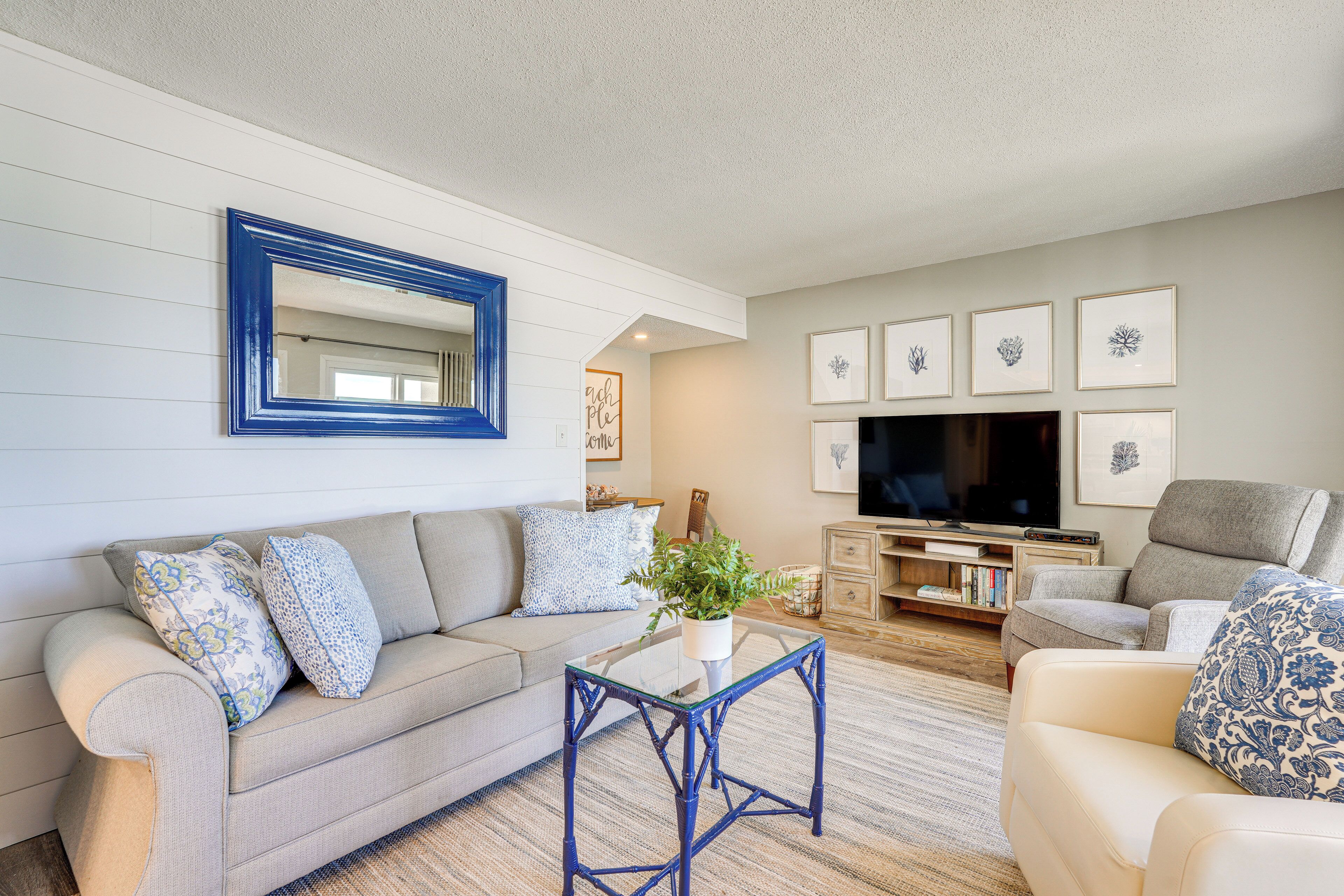 A living room with a sofa, a coffee table, a television, and framed artwork on the wall.