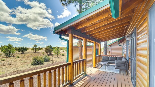 A wooden deck with a railing, outdoor seating, and a view of a desert landscape. - Near Lakes & Trails: Pet-friendly Cabin in Arizona (Overgaard)