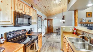A kitchen with wooden cabinets, a stove, a microwave, and a sink. - Near Lakes & Trails: Pet-friendly Cabin in Arizona (Overgaard)