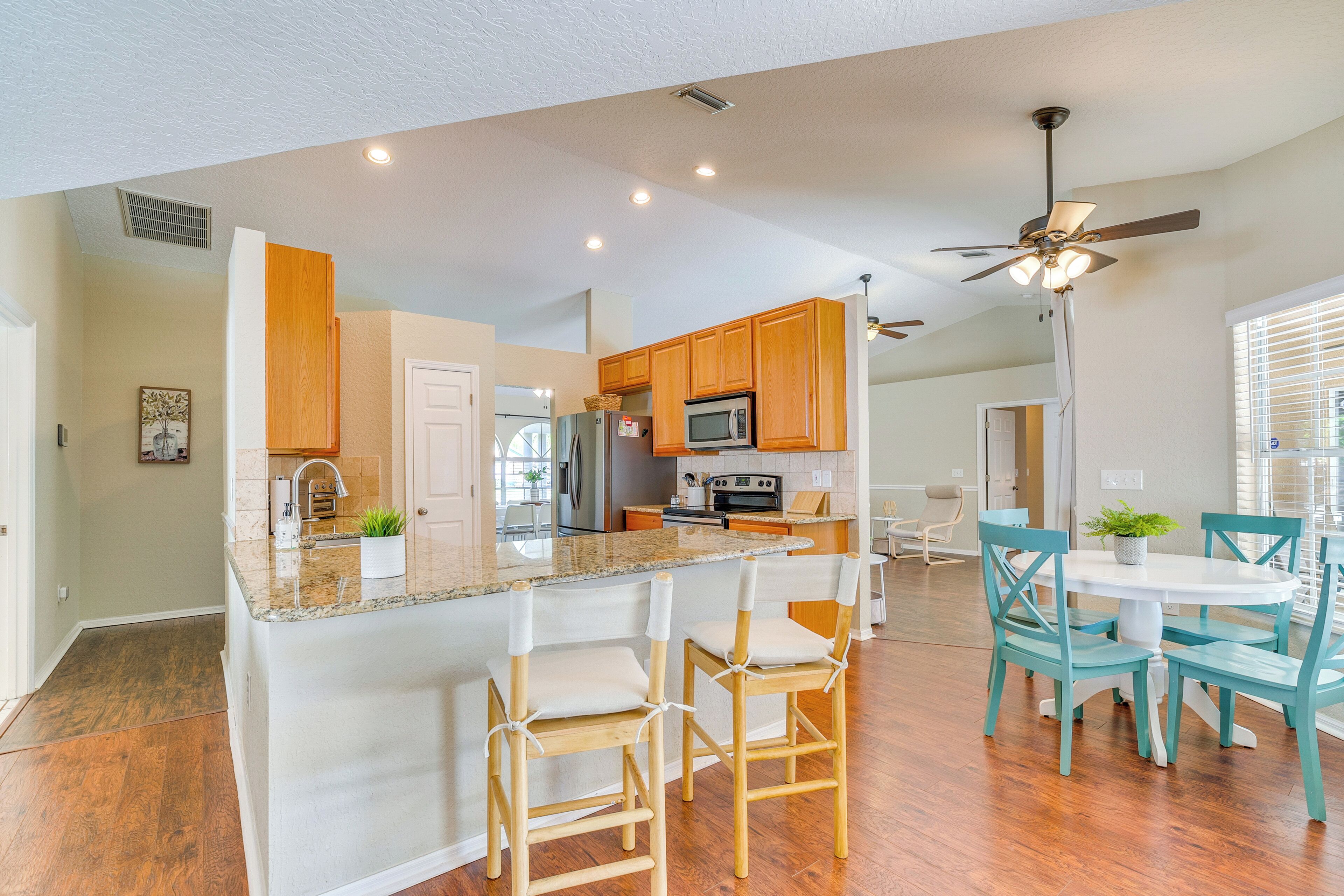 A modern kitchen with wooden cabinets, a granite countertop, and a central island with bar stools.