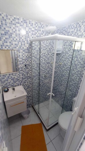 A bathroom with a glass shower enclosure, a sink, and a toilet. - Pousada Arpoador de Buzios (Búzios)