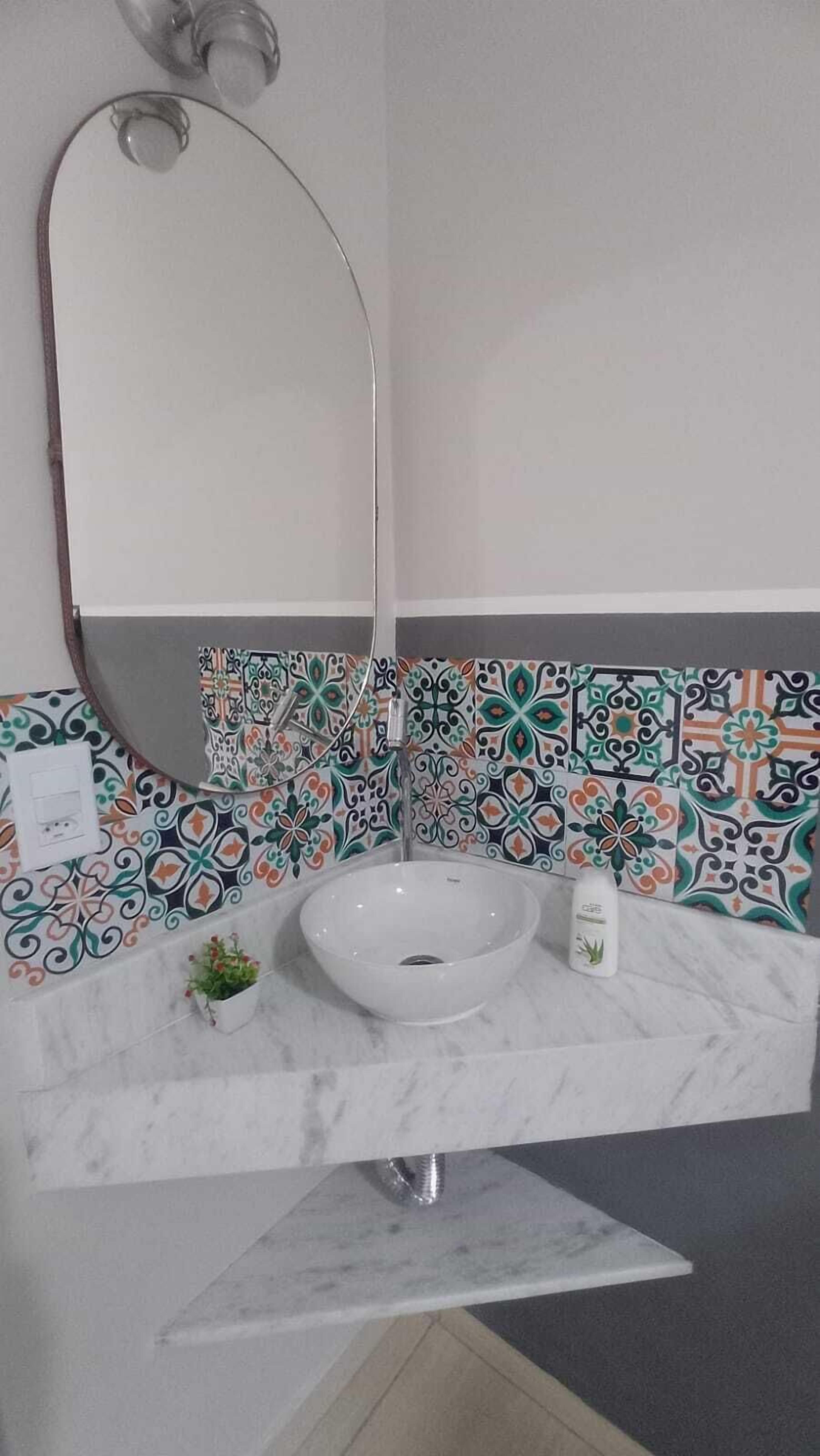 A bathroom with a white sink, a mirror, and a tiled backsplash.