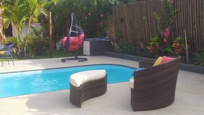 A swimming pool with wicker lounge chairs and a hanging chair. - FLATS ARPOADOR DE BÚZIOS (Búzios)
