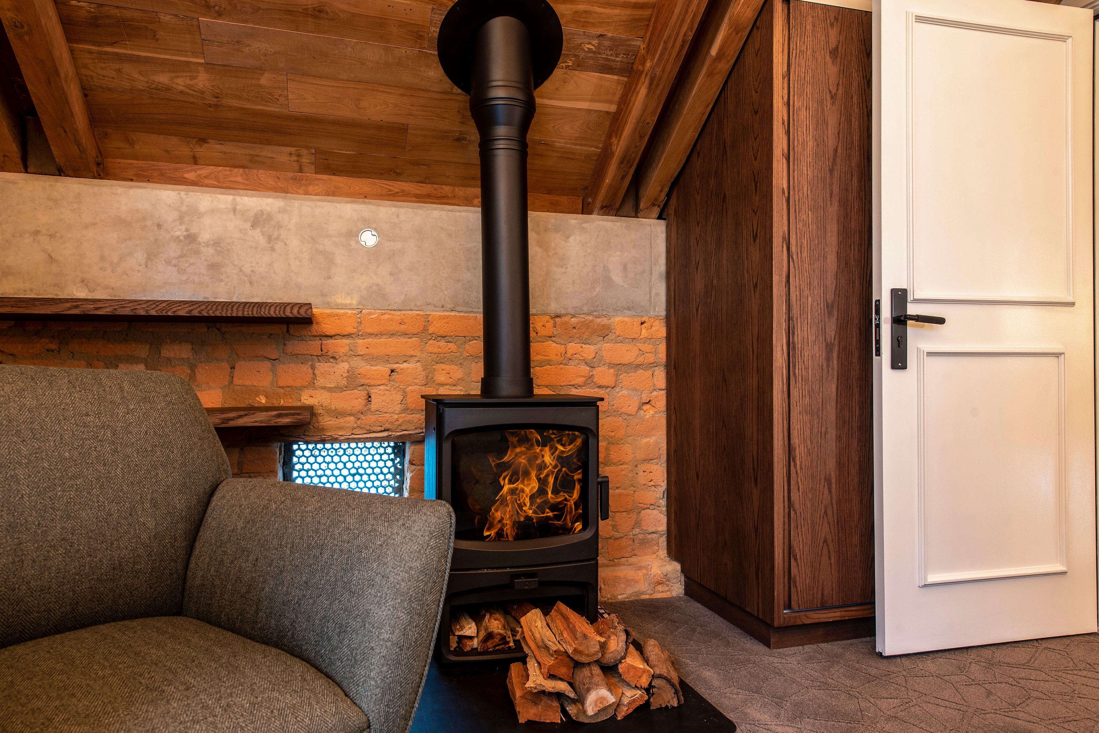 A cozy room with a wood-burning stove, a sofa, and a door.
