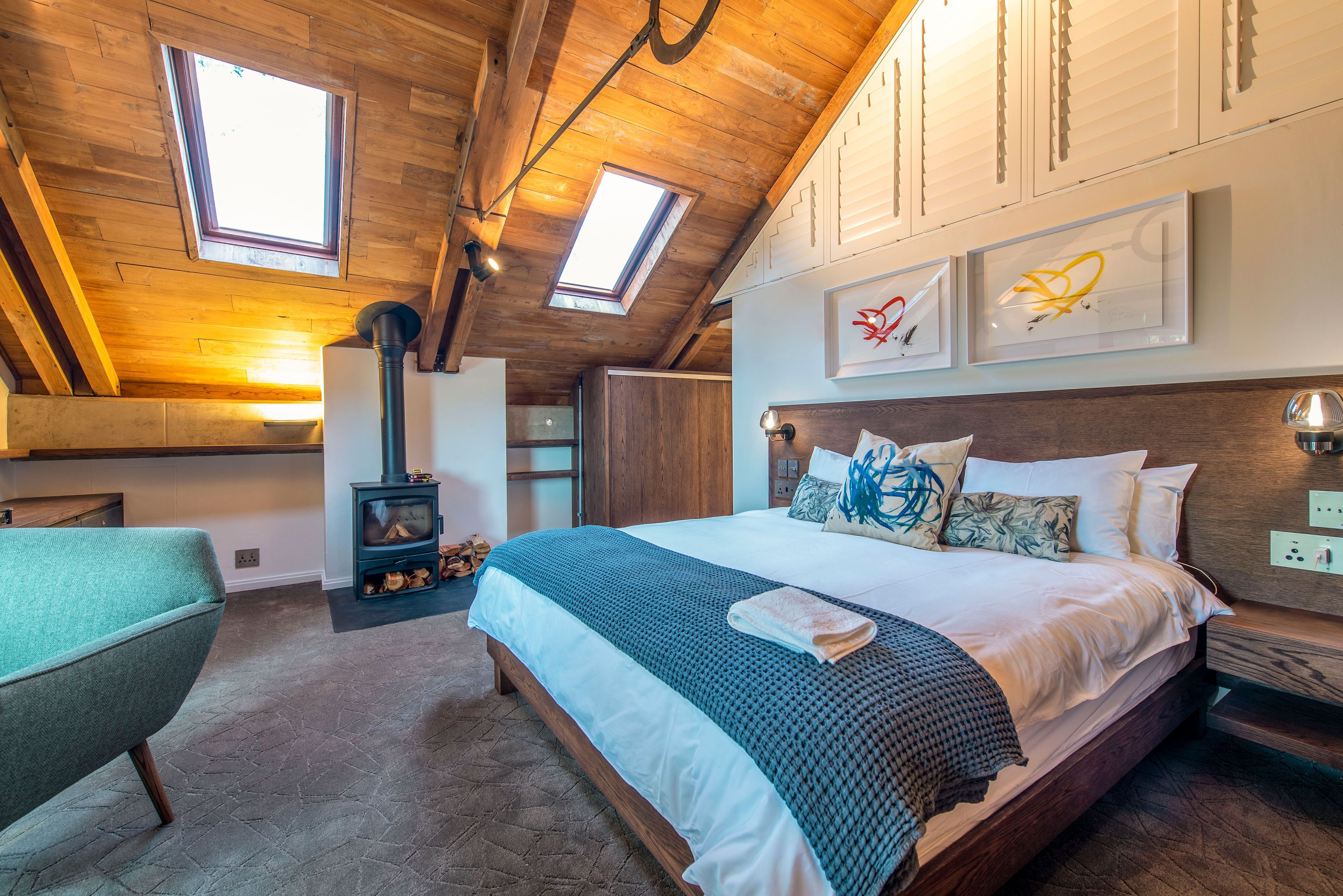 A bedroom with a large bed, a wooden ceiling, and a fireplace.