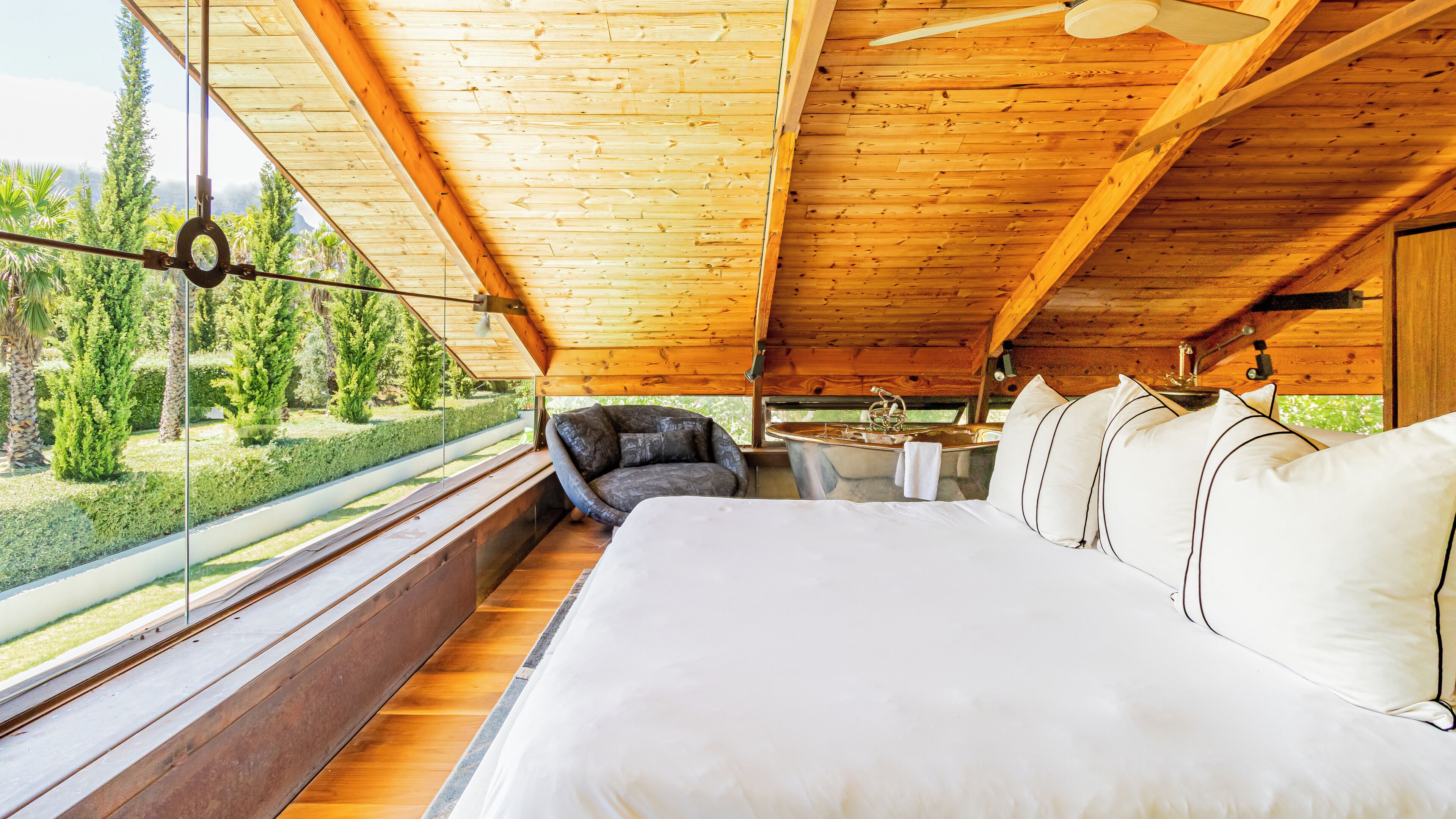 Une chambre avec un grand lit, une chaise, un lavabo et une vue sur l’extérieur.