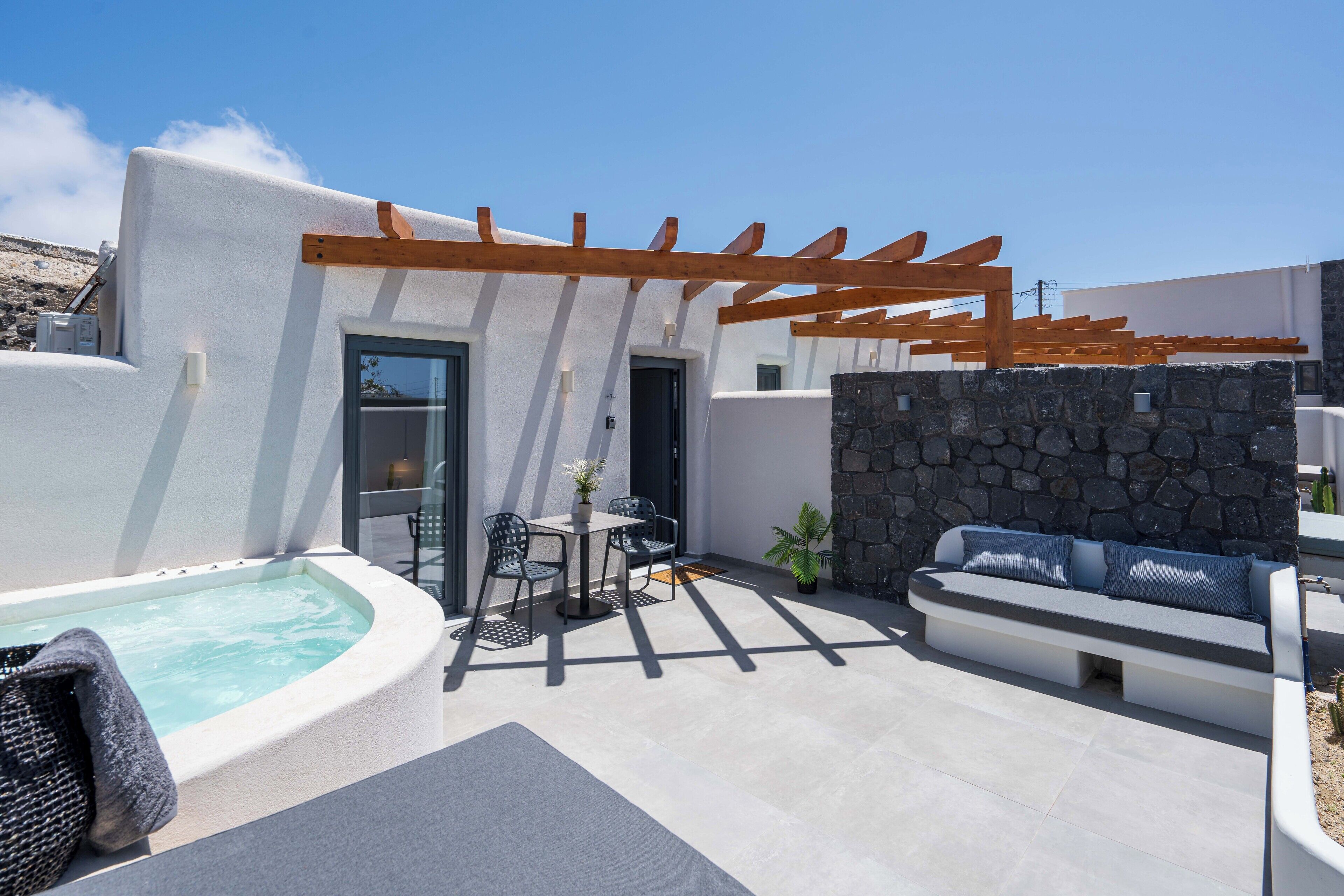 Un patio moderno al aire libre con jacuzzi, zona de estar y pérgola.