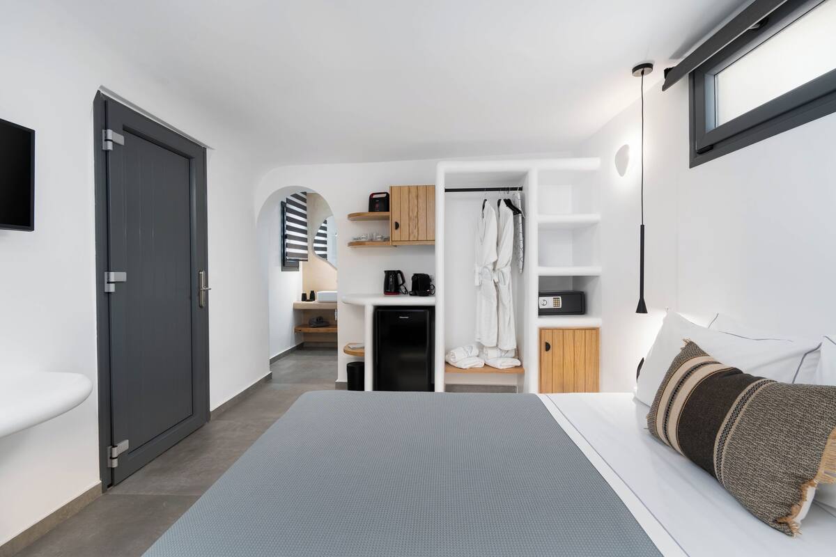 Una habitación de hotel moderna con una cama, un armario, un escritorio y una pequeña kitchenette.