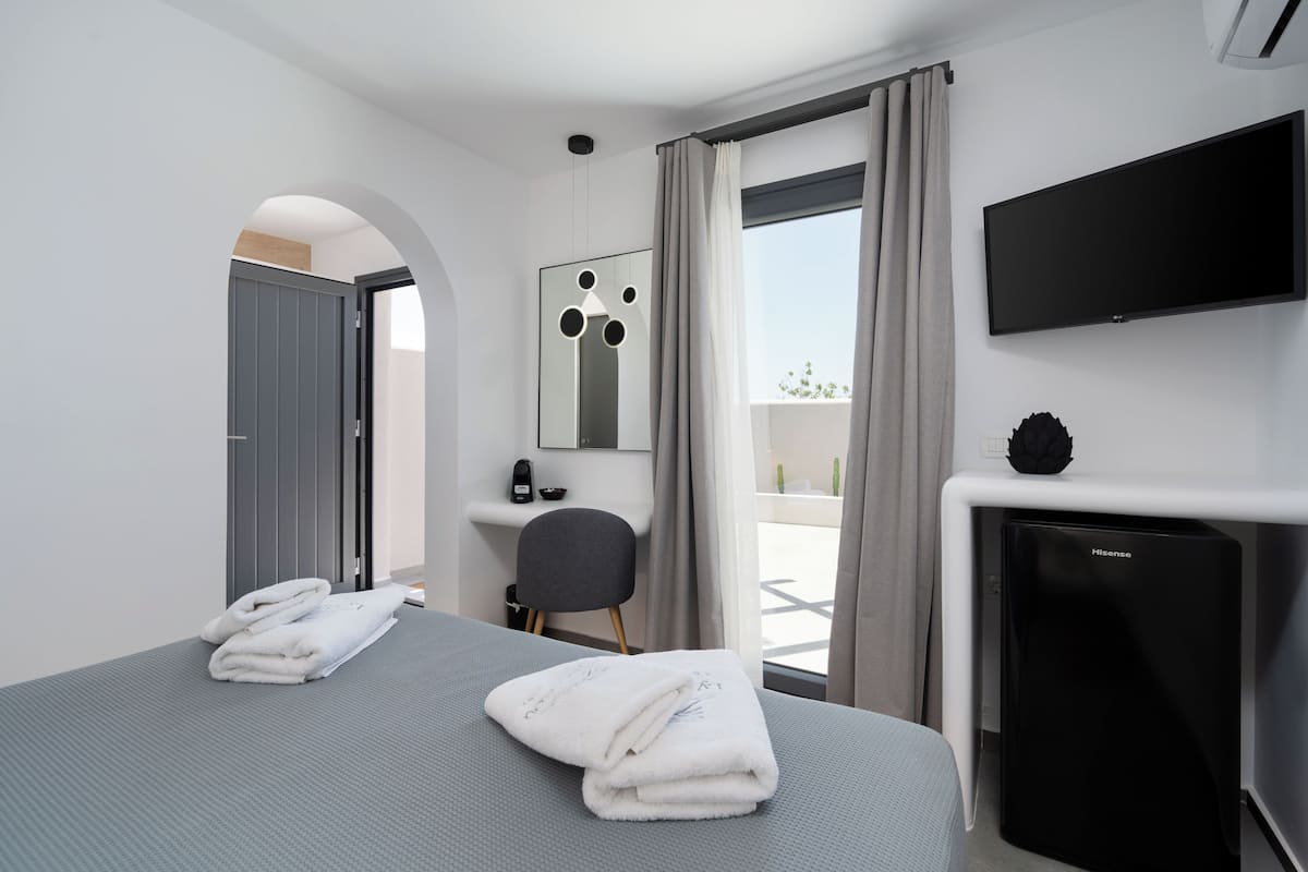 Una habitación de hotel moderna con cama, escritorio, televisor y vistas al exterior.