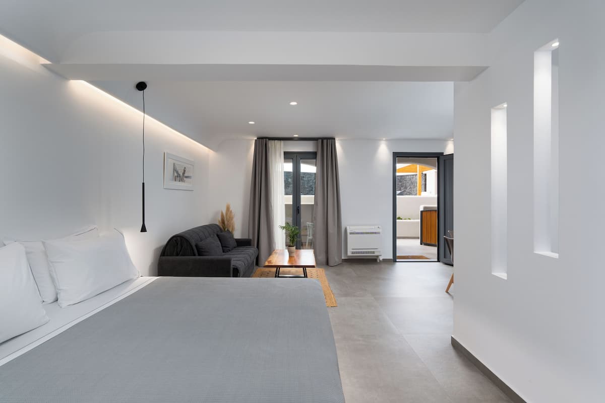 Habitación de hotel moderna con una cama grande, un pequeño espacio de estar, un escritorio y vistas al exterior.