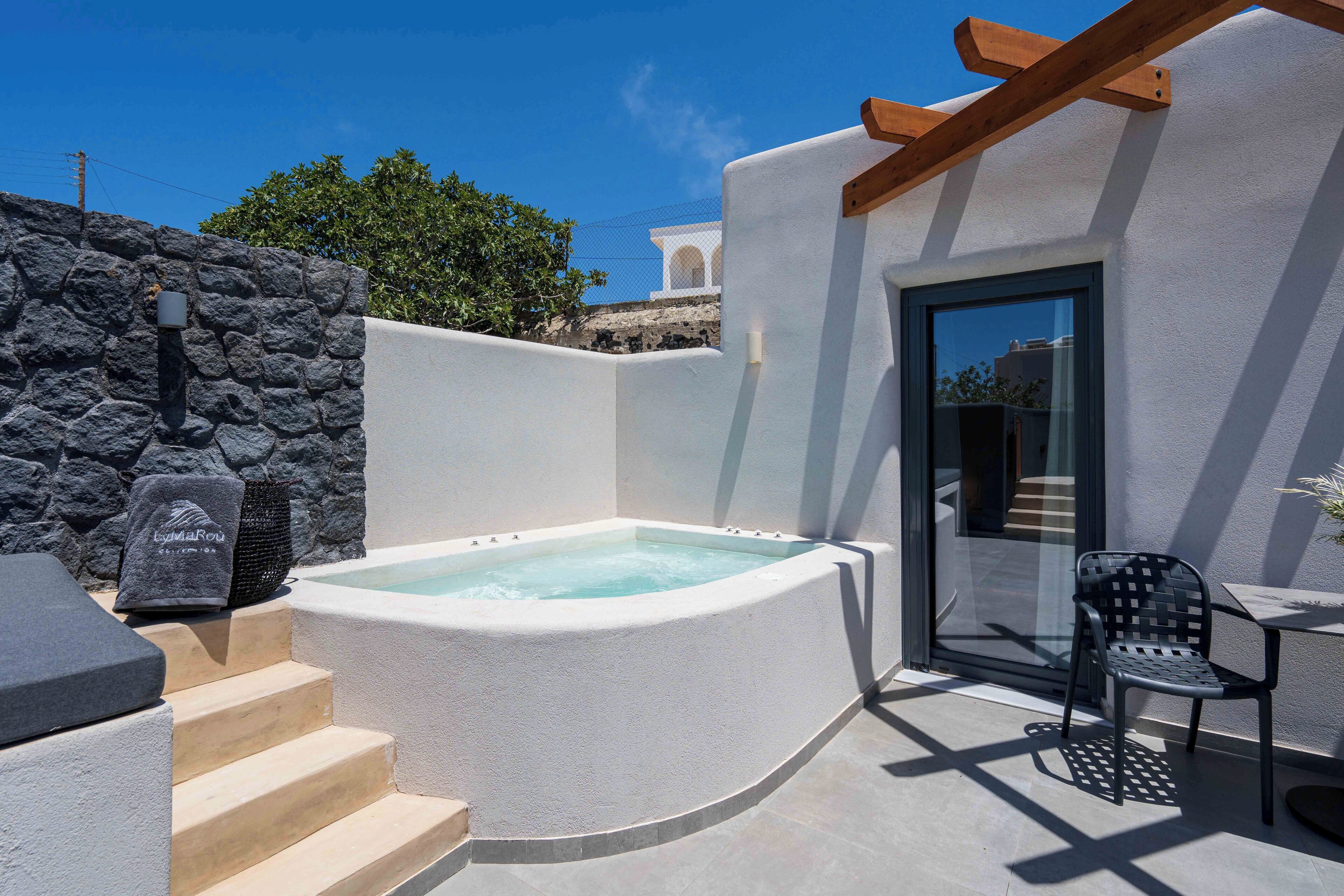 Un espace spa comprenant un jacuzzi, des sièges extérieurs et un mur en pierre.