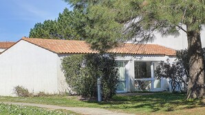 A single-story house with a tiled roof, a visible front door, and a small porch area. - Maison Dans Résidence Avec Piscine (Dolus-d'Oléron)