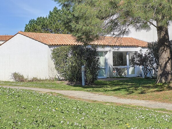Una casa de una sola planta con techo de tejas, una puerta principal visible y un pequeño porche.