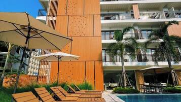 Un hotel moderno con zona de piscina, tumbonas y un cartel llamativo que dice 'REMEMBER' en el edificio.