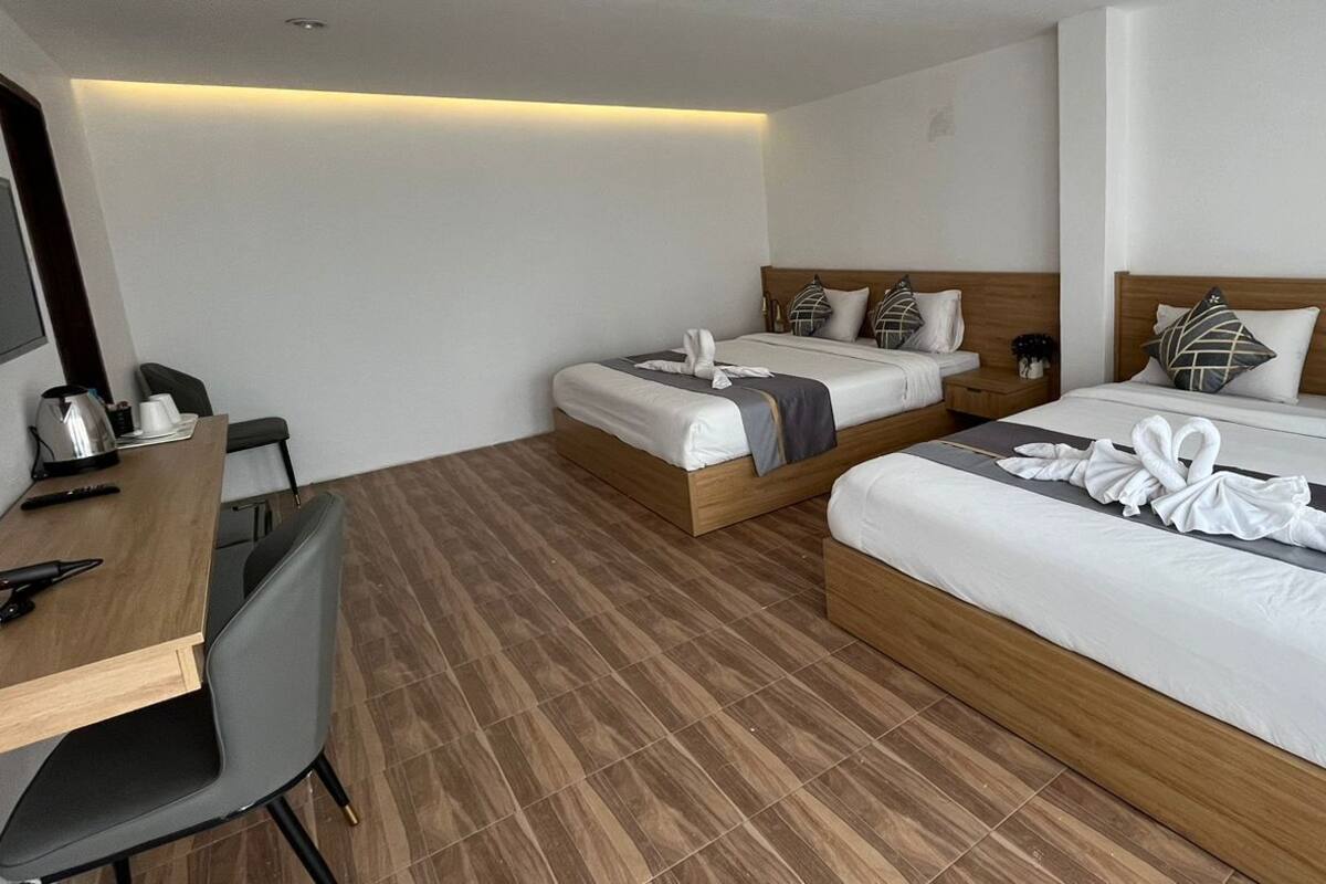 Ein Hotelzimmer mit zwei Betten, einem Schreibtisch und einem Stuhl.