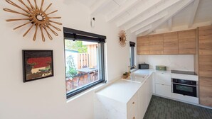 Een moderne keuken met witte kasten, een marmeren aanrechtblad en uitzicht naar buiten.