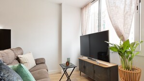 A living room with a sofa, a coffee table, a TV, and a plant.