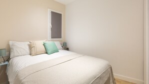A bedroom with a bed, two bedside tables, a window, and a door.