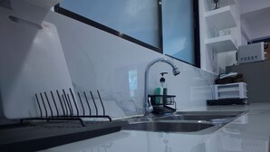 A modern kitchen with a stainless steel sink, a black faucet, and a soap dispenser. - Boracay Luxury Apartments (Boracay Island)