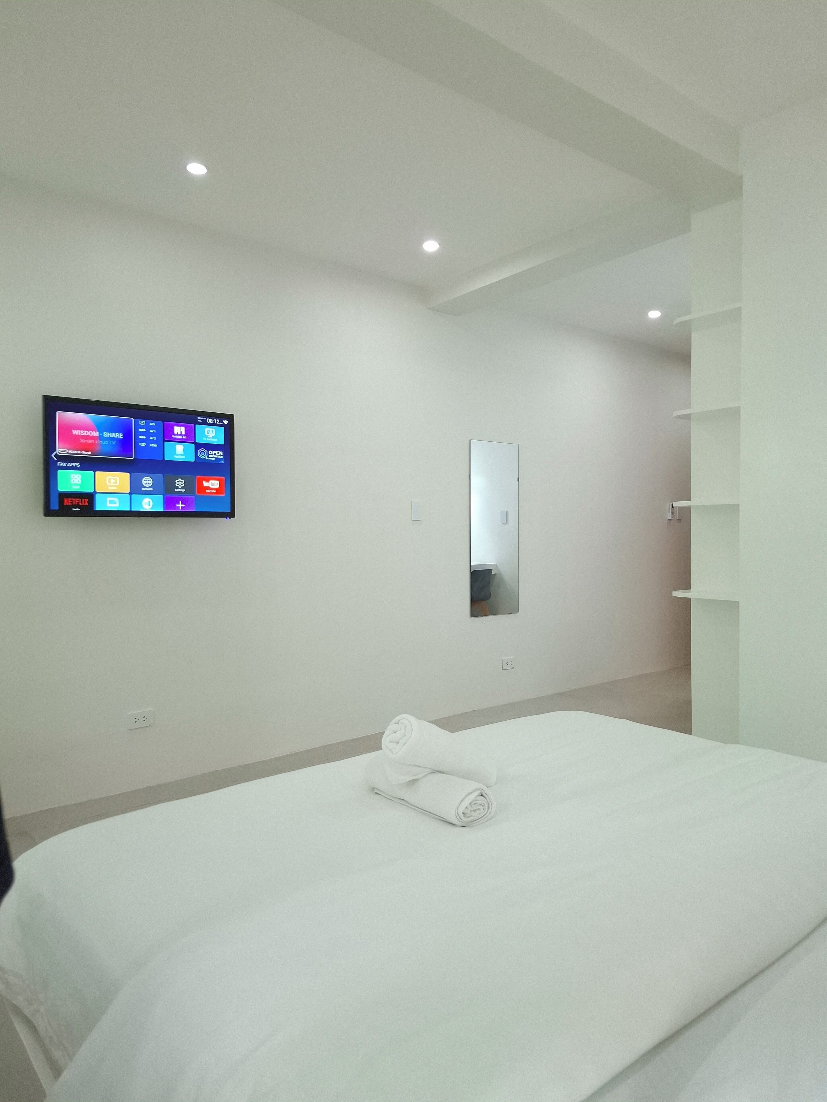 Een moderne hotelkamer met een groot bed, een flatscreen televisie aan de muur, een spiegel en een inbouwkast.