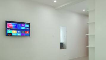 Een moderne hotelkamer met een groot bed, een flatscreen televisie aan de muur, een spiegel en een inbouwkast.