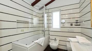 A modern bathroom with a bathtub, shower, bidet, and toilet.
