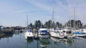 Ein Yachthafen mit verschiedenen Schiffen, ruhigem Wasser und blauem Himmel.