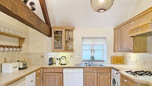 Eine Küche mit Holzausstattung, einem Geschirrspüler, einer Waschmaschine, einem Toaster und einem Wasserkocher.