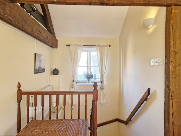 A staircase with wooden railings and a wicker chair at the bottom.