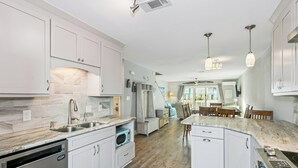 A modern kitchen with white cabinetry, a marble countertop, and a built-in dishwasher.
