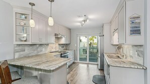 A modern kitchen with marble countertops, pendant lighting, and a built-in island with seating.