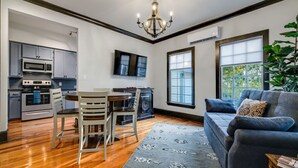 A modern kitchen with built-in appliances, a dining area with chairs, a large window, and a blue sofa in a living room. - 25% Off August!  LBJ Ste, 1 Block To Downtown* (Marble Falls)