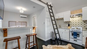 A modern kitchen with white cabinets, a wooden bar counter, a ladder, and a stove. - 25% Off August! Austin Suite, 1 Block To Downtown* (Marble Falls)