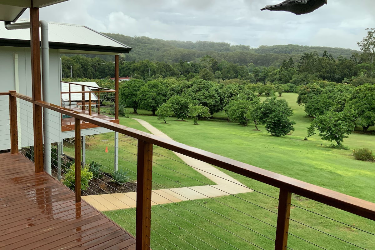 Una terraza de madera con vistas a un paisaje verde exuberante y una jaula colgante.