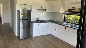 Een moderne keuken met witte kasten, een roestvrijstalen koelkast en een zwart aanrecht.