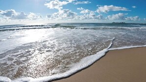 Een strand met golven die rustig op het strand spoelen onder een heldere lucht.