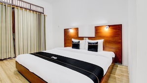 A hotel room with a large bed, wooden headboard, and a curtain with a metal rod. - Capital O 93873 Sokkyo Homestay (Ngaglik)