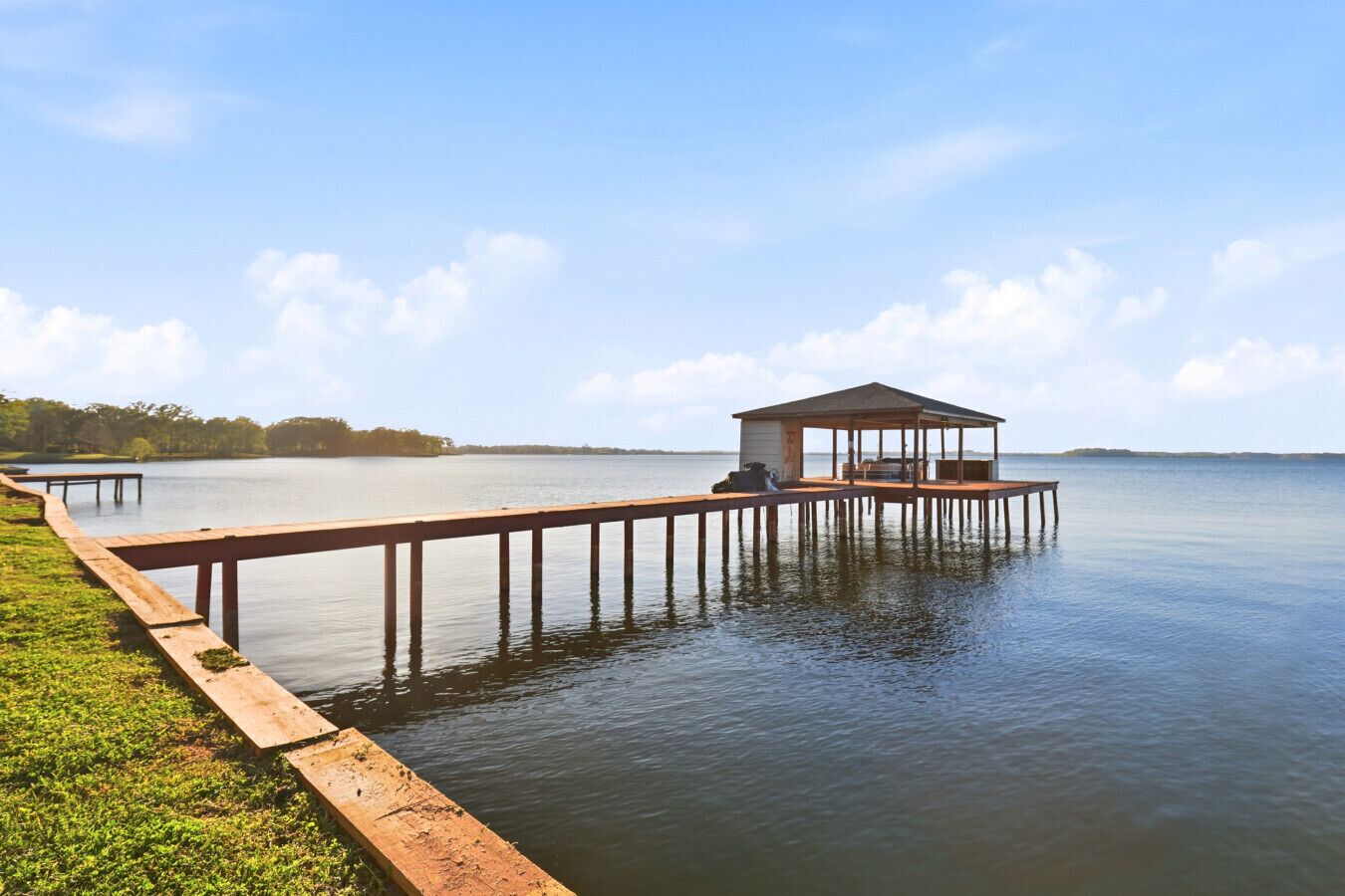Un muelle de madera que se adentra en aguas tranquilas, con una estructura cubierta al final.