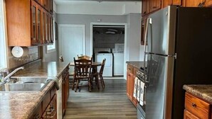 Une cuisine dotée de meubles en bois, d’un réfrigérateur en acier inoxydable, d’un four encastré et d’un coin repas avec des chaises en bois.