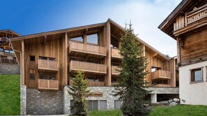 Un edificio in legno a più piani con balconi, fondamenta in pietra e un cartello con la scritta 'Hotel Neiges'.