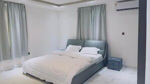 A modern bedroom with a bed, nightstand, and air conditioning unit.