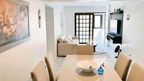 Un salon moderne avec une table à manger, des canapés de couleur beige et un grand tableau abstrait.