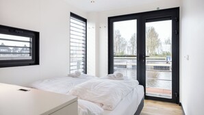 Une chambre d’hôtel moderne avec deux lits, une grande fenêtre et une vue sur un canal.
