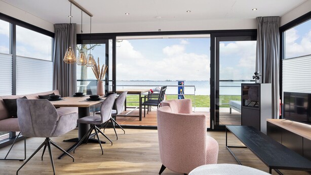 Un intérieur moderne comprenant un coin repas, des sièges et une vue sur la mer.