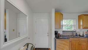 Une cuisine avec des meubles de rangement en bois, un plan de travail, un évier et une fenêtre avec des stores.