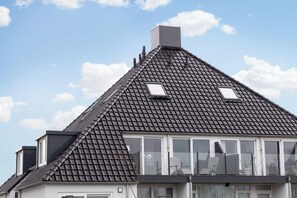 A residential building with a steeply pitched roof, dormer windows, and a visible chimney.