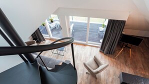 Una sala moderna con escaleras, un televisor y vistas a la terraza exterior.