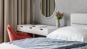 A modern bedroom with a bed, a desk with a mirror, a chair, and a vase with flowers. - City Buzz Apartment - O2 Arena - Sleeps 6 (Prague)